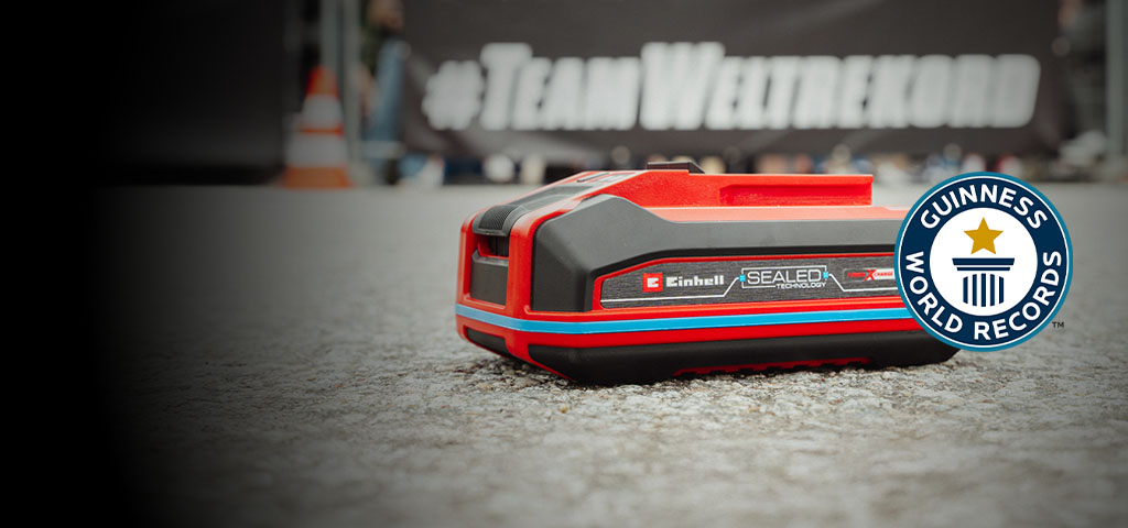 Batería Einhell SEALED Power X-Change 4.0 Ah sobre asfalto, con el logo de Guinness World Records "Record Holder" a la derecha.