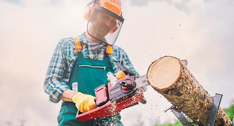 man cutting a tree with cordless chainsaw